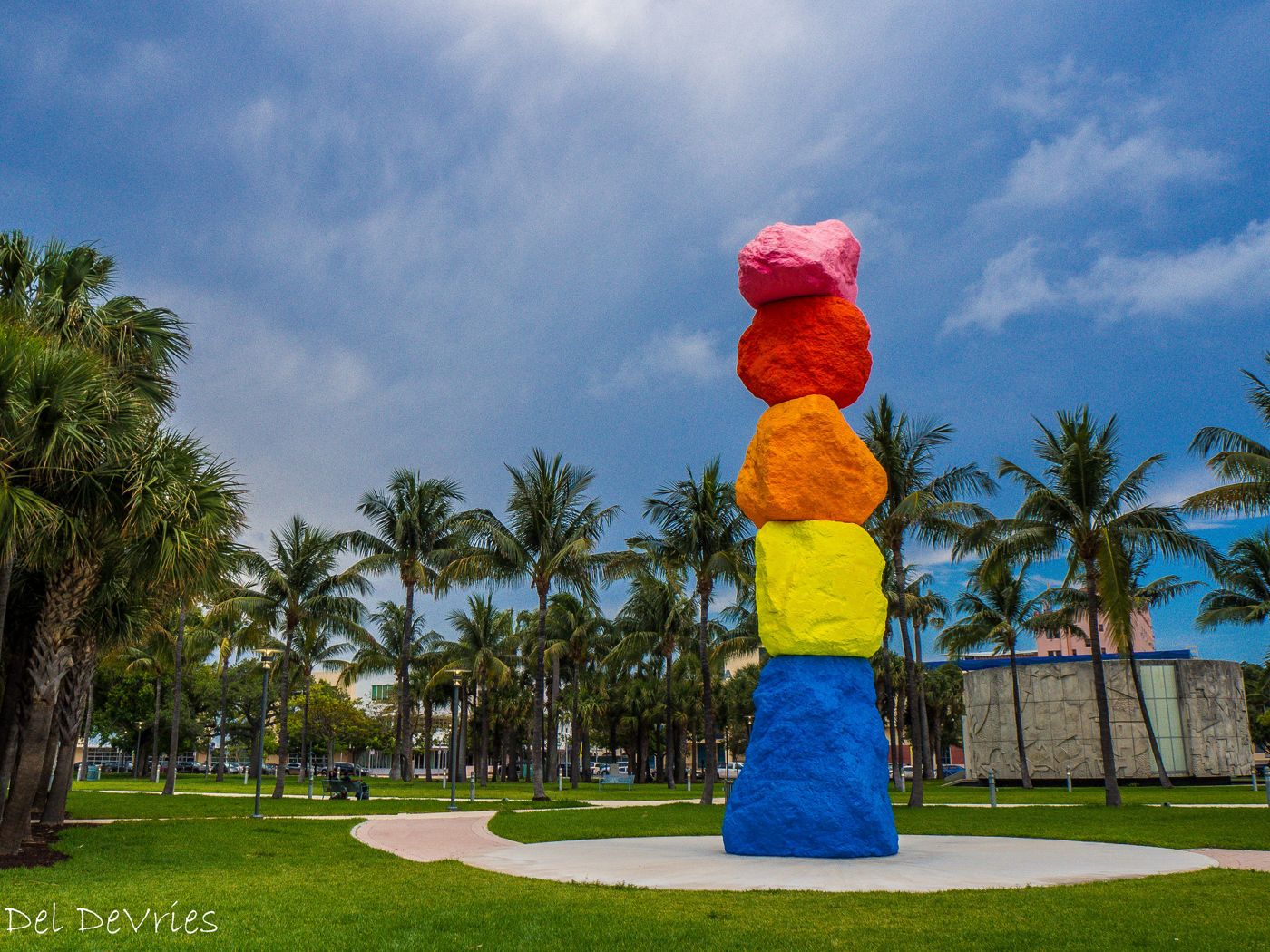 Miami Mountain sculpture against a blue sky with palm trees